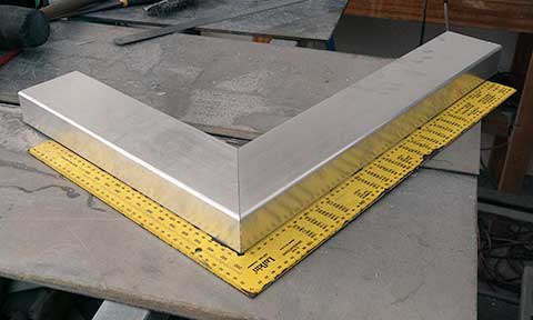 Two lengths of box section with mitred corners being checked with a framing square.