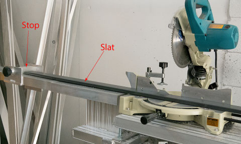 A slat being cut using a mitre saw stand with a stop